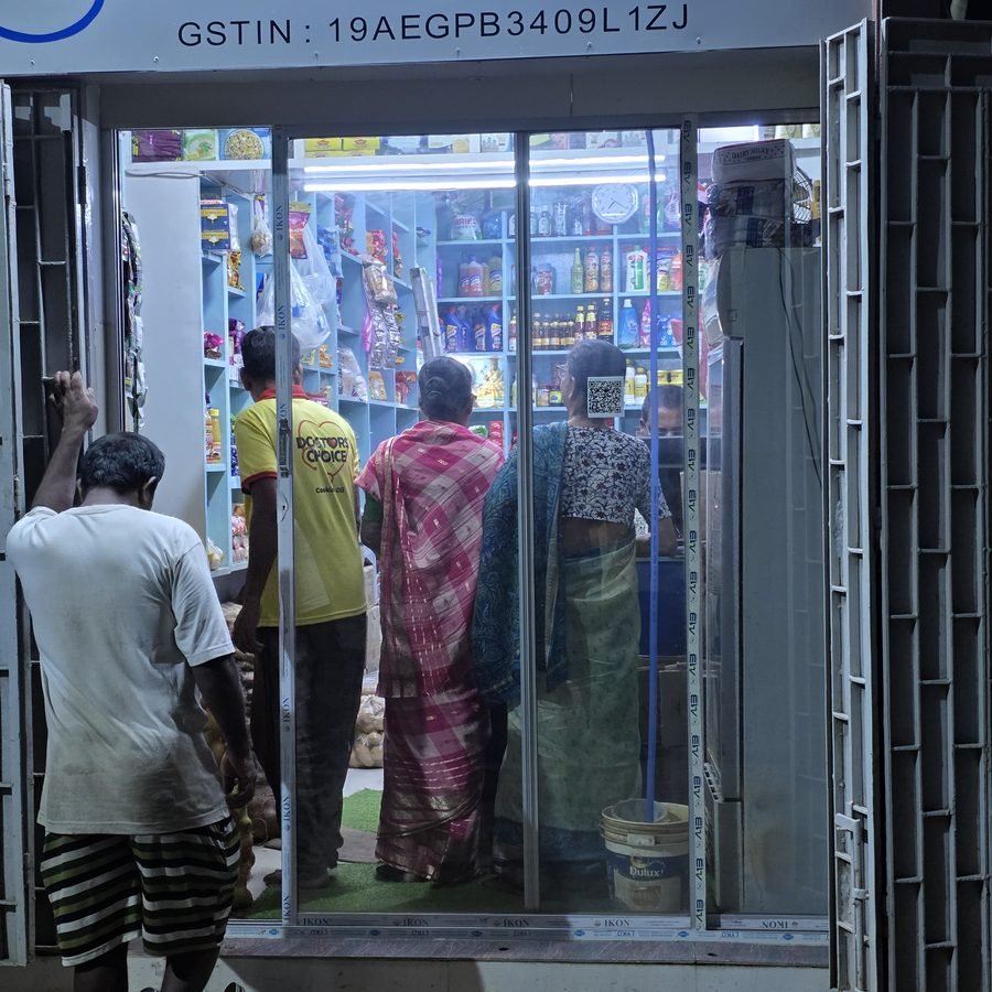 Customers gathered at the lit Ganapati shopfront during the evening rush.