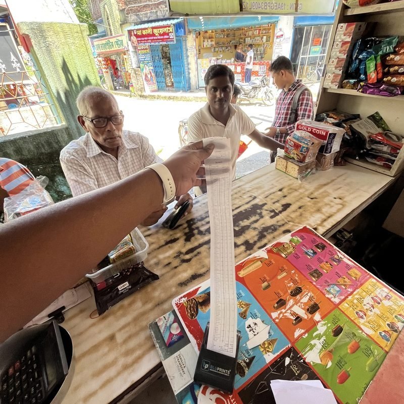A long computerised GST bill handed across the Ganapati counter in daylight, thermal printer on the desk.